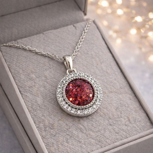Silver necklace with a red pendant in a gray box with blurred lights in the background ashes memorial pendant